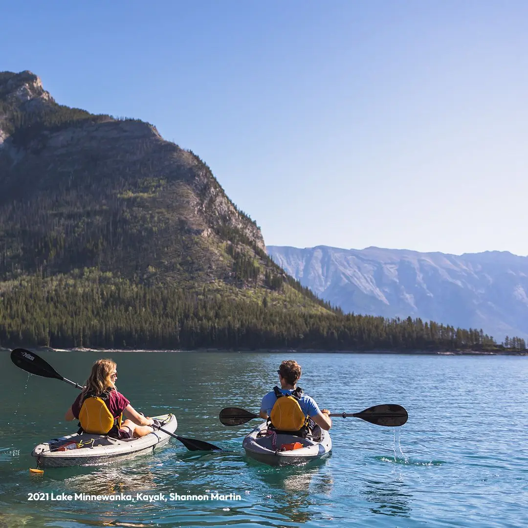 Guy and girl in kayak on lake with mountain in background