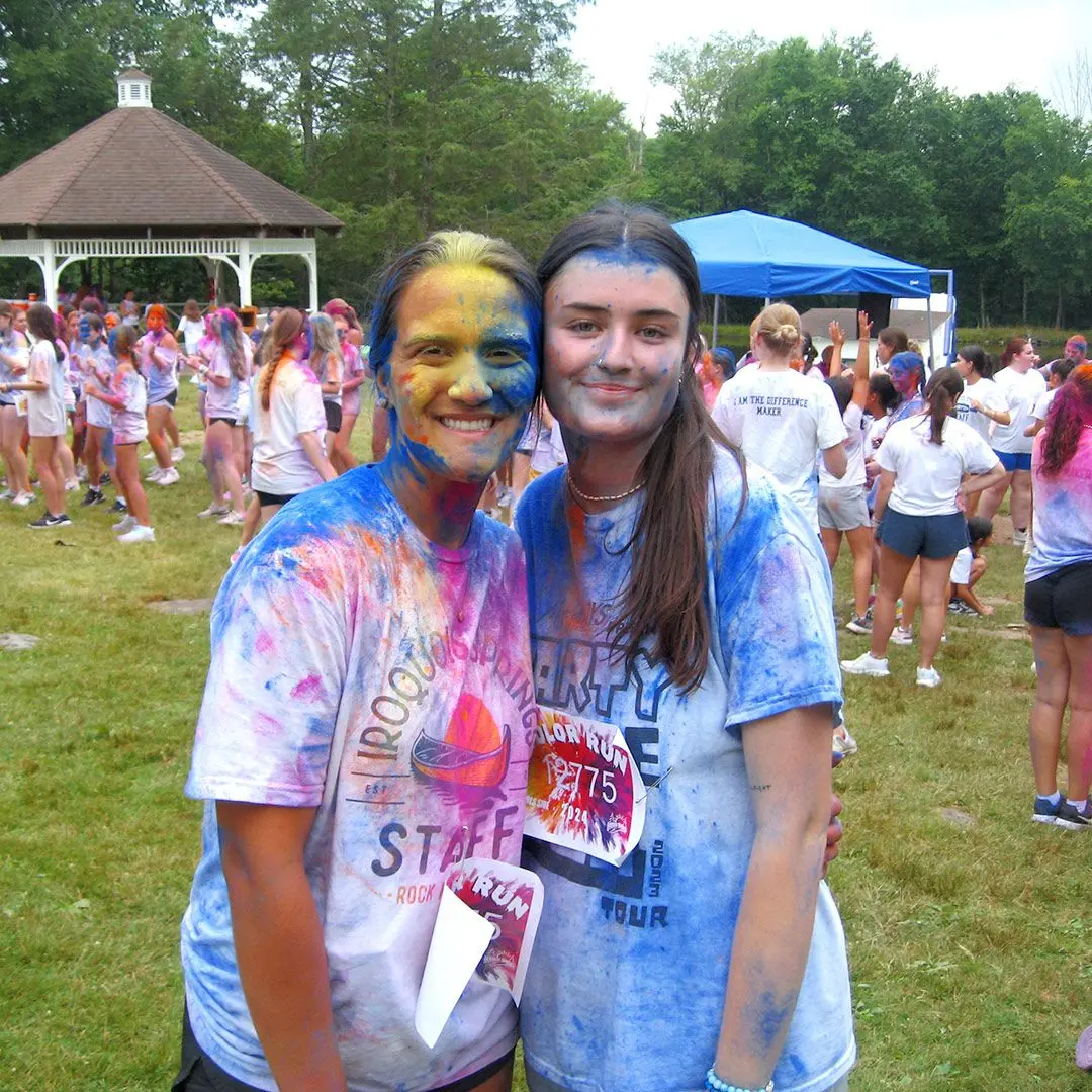 Two girls covered in powdered paint after taking part in a colour run at summer camp.