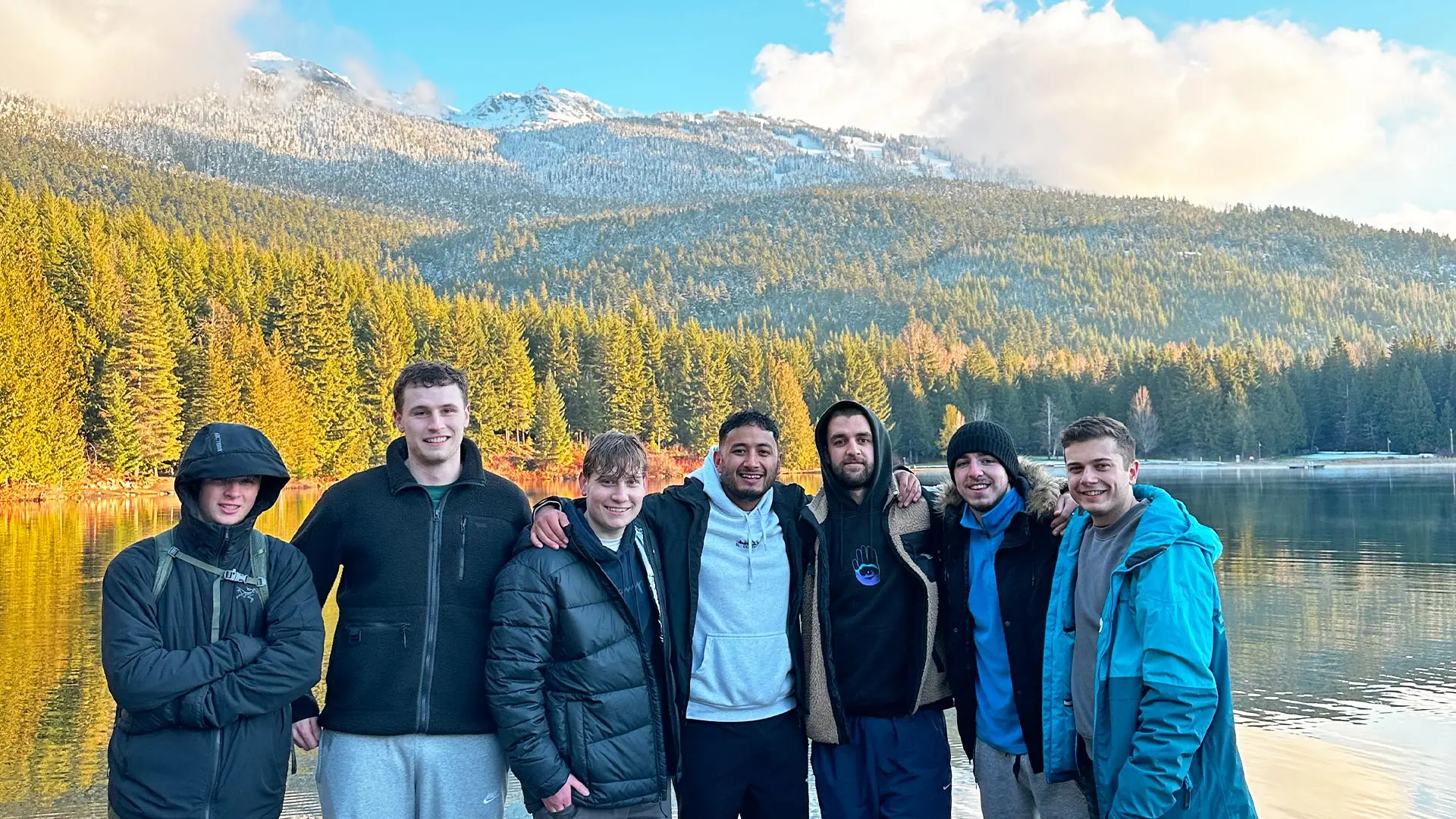 7 guys pose in front of lake