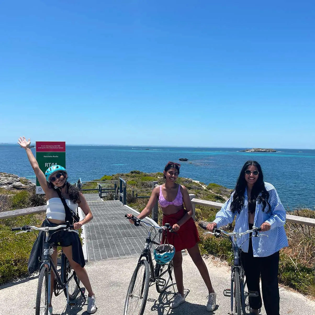 3 girls with bikes on coast on a sunny day