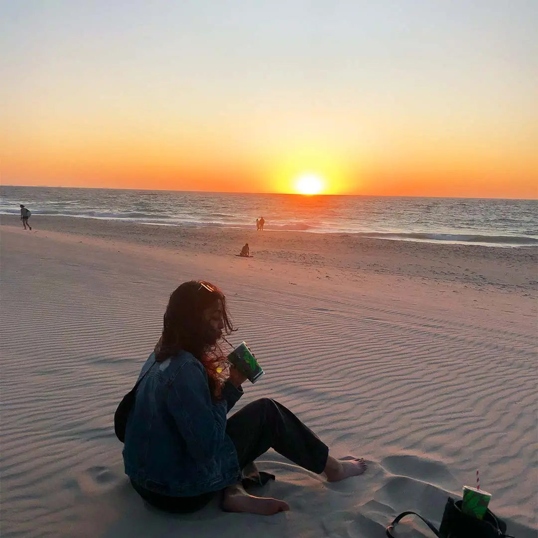 Girl drinks shake on beach sunset