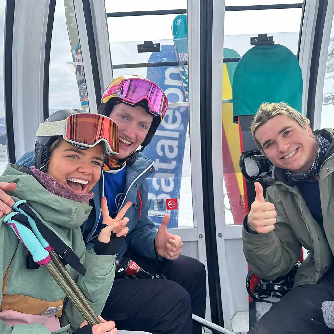 3 friends pose on ski-lift