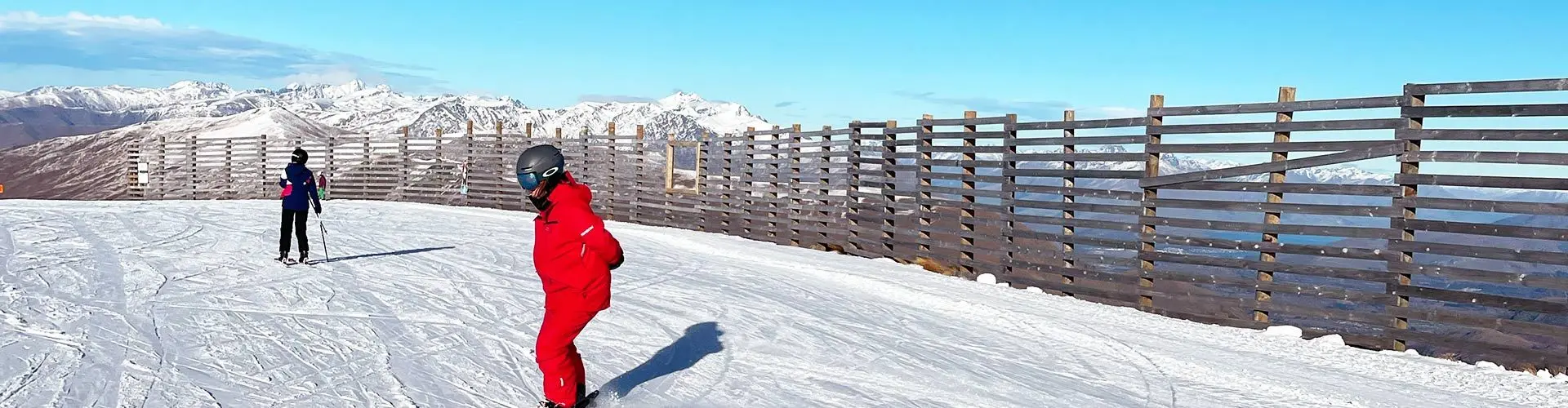 People skiing down slope on sunny day