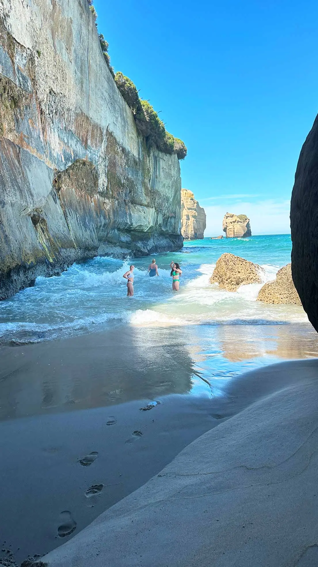 Girls swim beside cliffs