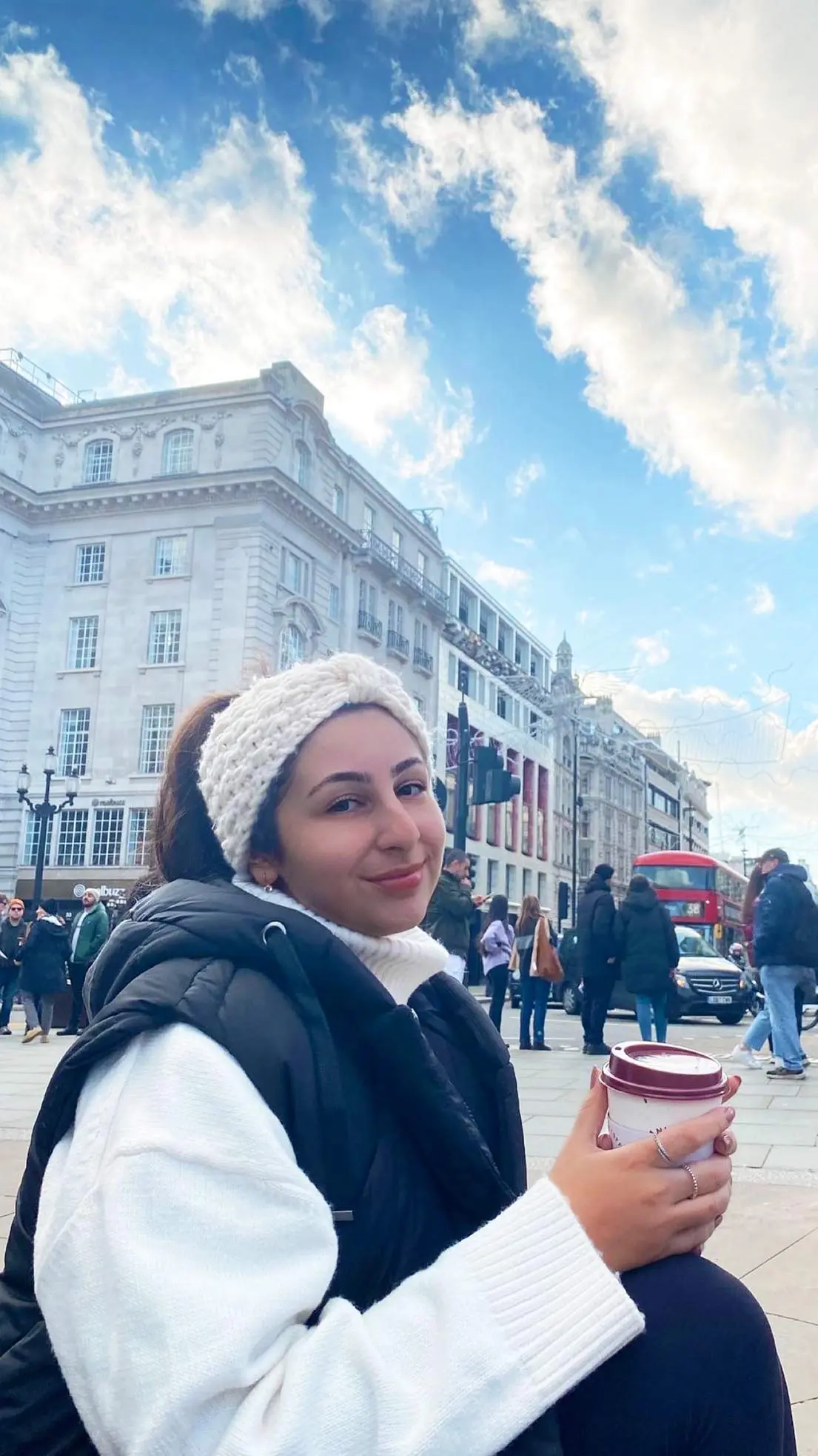 Girl smiles in London with coffee cup