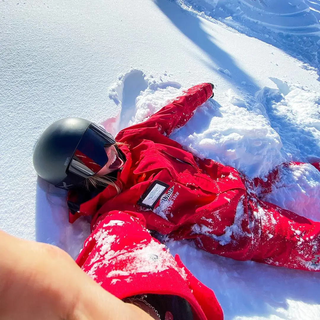 Person in red snow gear lies in snow