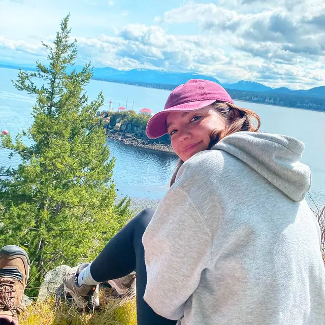 Girl smiles on lodge looking out over mountains.