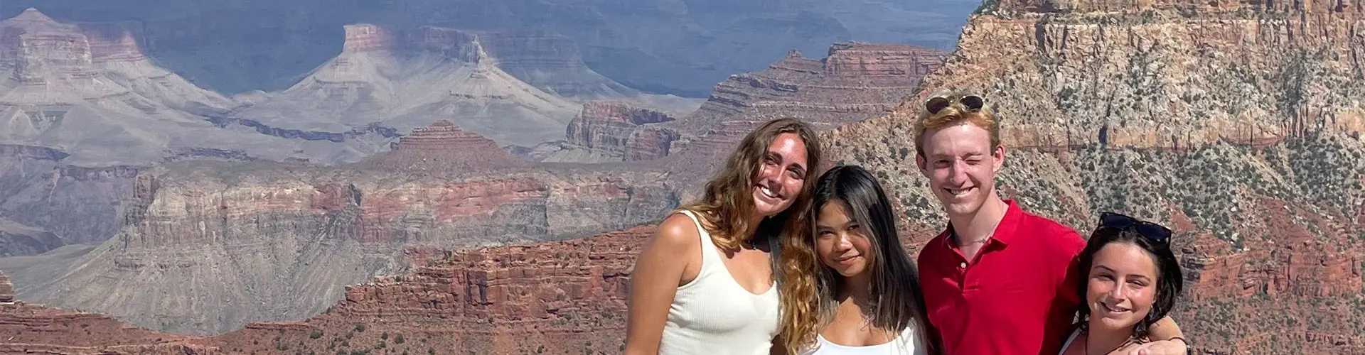 Three girls and one guy stand on the Grand Canyon.