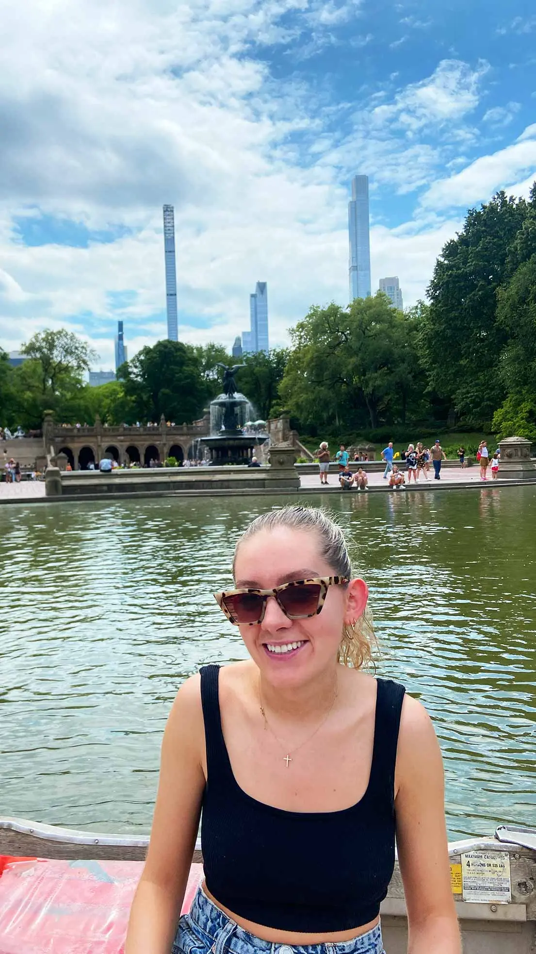 Girl sits on boat in Central Park with blue sky