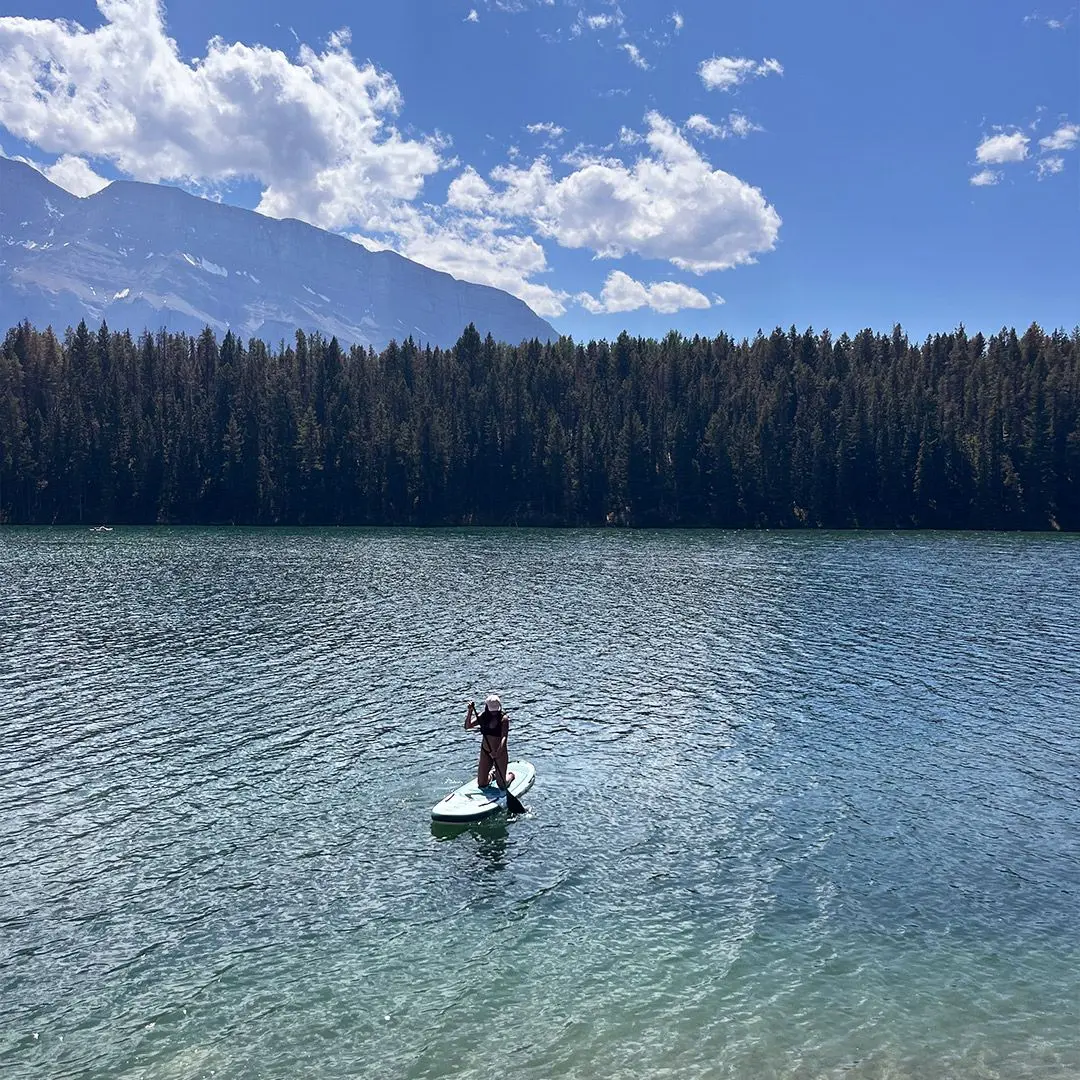 girl rows on paddle board on lake