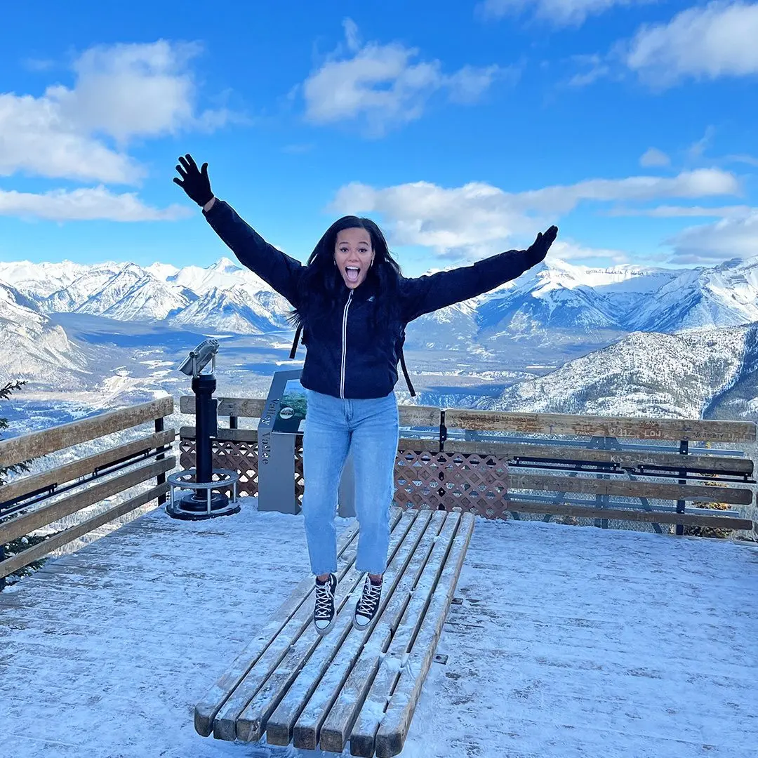 Girl jumping off table on snowy day with blue ski