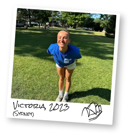 Victoria smiles in a grassy field at camp