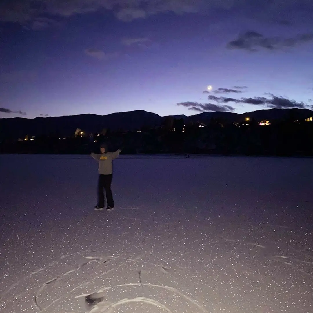 girl raises arms on snow at night