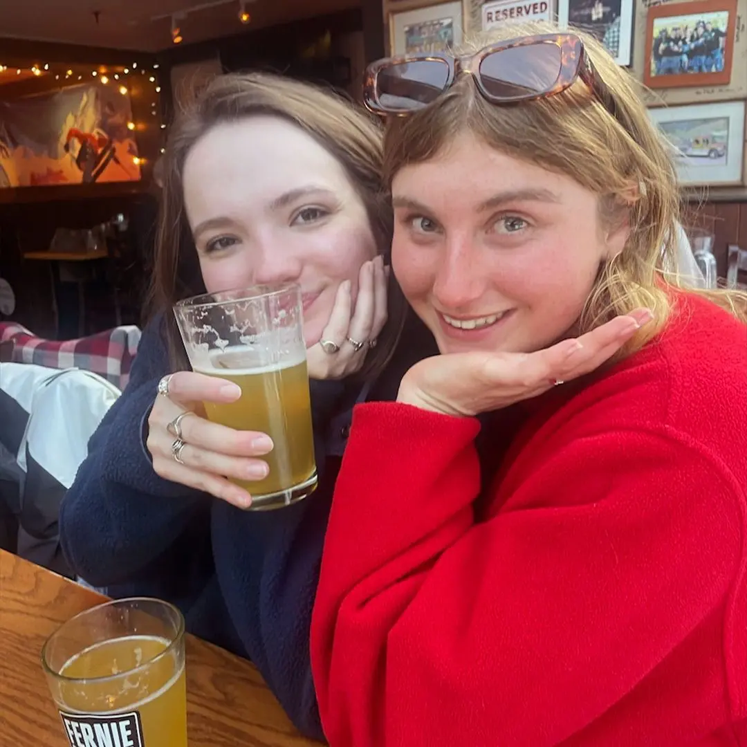 2 girls with drinks smile at camera