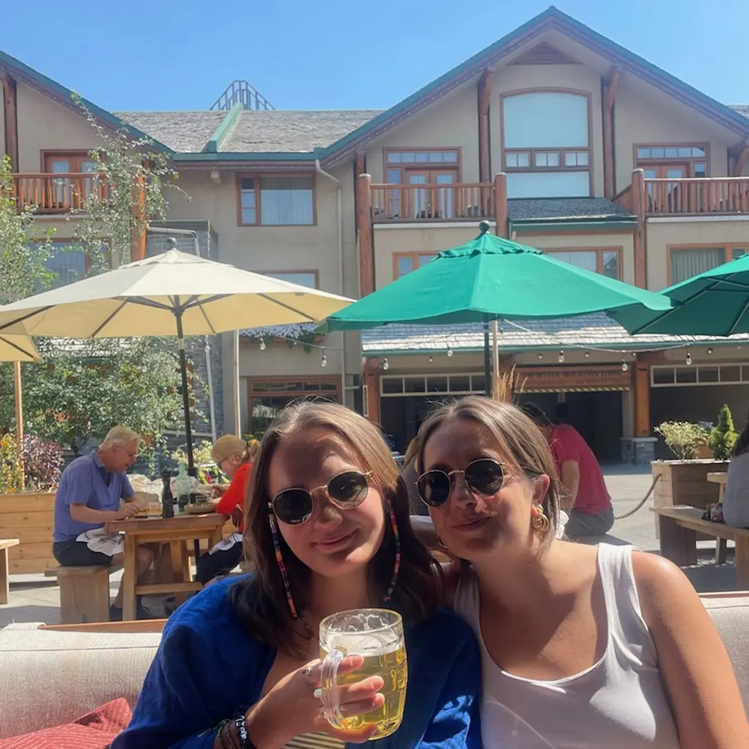 2 girls smile with beer on sunny day in bar